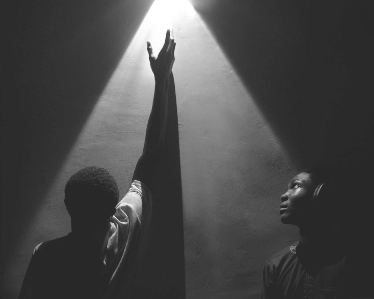 Two individuals in dramatic lighting expressing hope and aspiration.